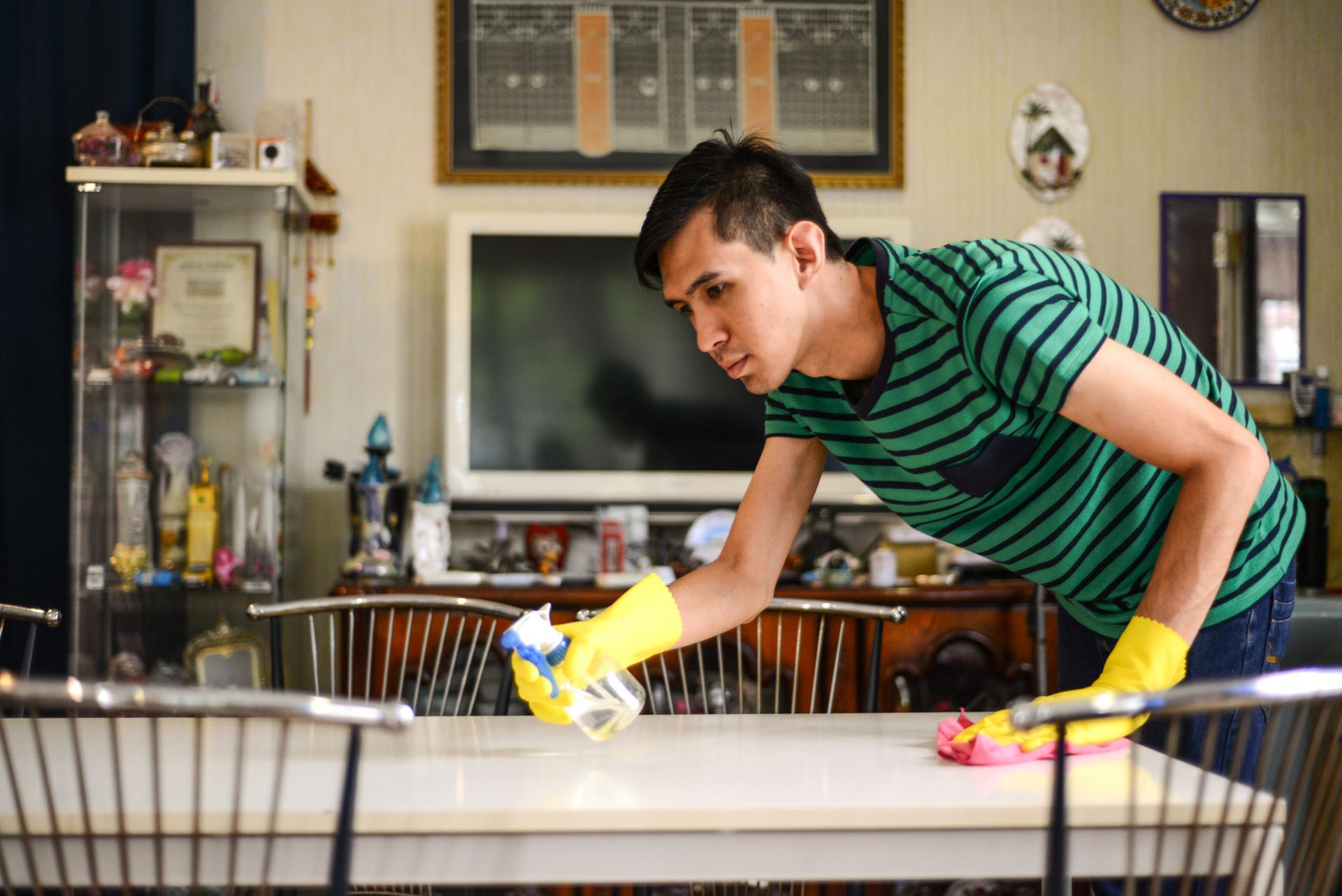 Jeune homme asiatique nettoyant la table à la maison